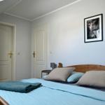 Schlafzimmer mit Holzbett, blauer Bettwäsche und Bild an der Wand.