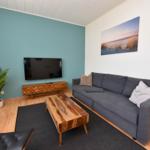 Wohnzimmer mit Sofa, Fernseher und Holztisch.