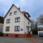 Drei-stöckiges Haus mit Terrasse und Garage. Vorhof mit gepflastertem Weg.