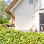 Terrasse mit Tisch, Stühlen und Sonnenschirm neben einem Haus mit Schiebetür.