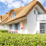 Haus mit Strohdach, Balkon und Gartenmöbeln im Freien.