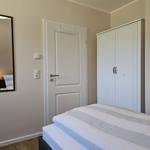 Schlafzimmer mit Bett, Kleiderschrank und Spiegel an der Wand.