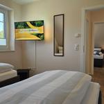 Zwei Betten, Fernseher und Spiegel. Durchgang zu weiterem Schlafzimmer.