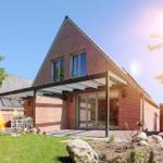 Moderne Villa mit Terrasse und Garten unter blauem Himmel.