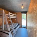 Zimmer mit Doppelstockbett, Holzwand und Fenster zum Ausblick.