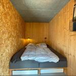 Schlafzimmer mit Bett, Holzwänden und Wandlampe.
