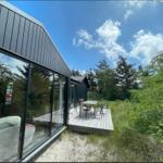 Moderne Unterkunft mit Terrasse, Tisch und Stühlen im Grünen.