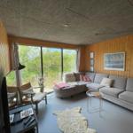 Wohnzimmer mit Sofa, Fenster und Holzwand.