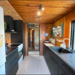 Küche mit Holzwänden, schwarzen Schränken und Fensterblick.