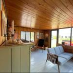 Wohnraum mit Holzwand und -decke, Sofa, Fenster und Schrank.