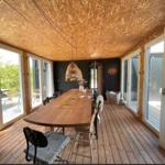 Esszimmer mit Holztisch, Stühlen und Glasfronten zur Terrasse.