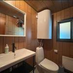 Badezimmer mit Waschbecken, Toilette und Spiegel an Holzwand
