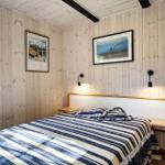 Schlafzimmer mit Holzwand, Bett und Fenster mit Blick auf Bäume.