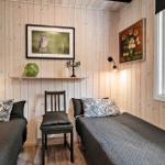 Zwei Betten, Holzwand, Fenster mit Blick auf Wald, Wandbild und Stuhl.