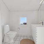 Bathroom with toilet, sink, and small window.