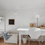 A room with bunk bed, desk and chair. Wall with chalkboard and lamps.