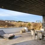 Deck with lounge, table and chairs. View of dunes and sky.