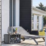 Deck with lounge chair and firewood stack in front of modern house