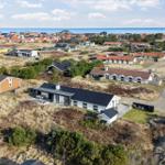 Modern house with terrace, surrounded by dunes and sea view.