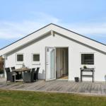 Modern white holiday home with terrace and garden table. House number 25. Danish flag attached.