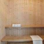 Sauna with wooden walls, bench, and towels.