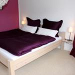 Ein Schlafzimmer mit Bett, Nachttisch und Vorhängen.