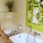 Bad mit Dusche, Toilette und Badewanne. Wandbild mit Orchideen.