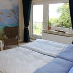 Schlafzimmer mit Bett, Stuhl und Fenster zur Terrasse.