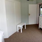 Schlafzimmer mit weißer Bettbank, Schrank und Schrank mit Schubladen.