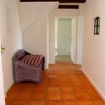 Flur mit Terrakottboden, Sitzbank und Holzbalken an der Decke.