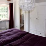 Schlafzimmer mit Doppelbett, weißem Schrank und Fenster mit Blick auf Garten.