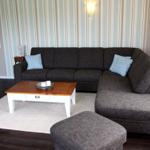 Ein Wohnzimmer mit grauem Sofa, Holztisch und Streifenwand.