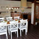 Esszimmer mit Tisch, Stühlen und Küchenbereich mit Backsteinwand.