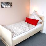 Ein Schlafzimmer mit einem Bett, einem Stuhl und einer Wanddekoration.