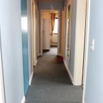 Flur mit blauen Wänden und grauem Teppichboden. Türen und Spiegel sind sichtbar.