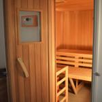 Eine Sauna mit Holzbank und Tür mit Bedienfeld.