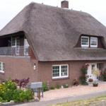 Haus mit Strohdach, Balkon und Blumenbeet vor der Tür