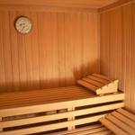Sauna mit Holzbank und Temperaturuhr an der Wand.
