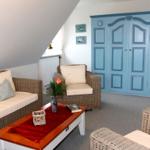 Wohnzimmer mit blauem Schrank, Wickermöbeln und Holztisch.