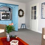 Wohnzimmer mit blauem Schrank, Wicker-Sofas und Kachelwand