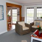 Wohnzimmer mit Rattanmöbeln, Fenstern und Wandfliesen.