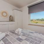 Schlafzimmer mit Bett, Schrank und Fensterblick auf Grünflächen