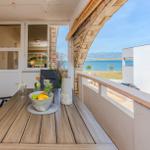 Terrasse mit Tisch, Stühlen und Meerblick. Tisch mit Obstschale und Getränken.