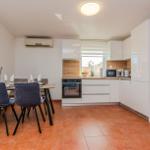 Küche mit Essbereich, weißen Schränken und Terrakottaboden.