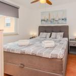 Schlafzimmer mit Bett, Nachttisch und Wandbild mit Segelbooten.