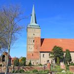 Historische Kirche mit Turm und rotem Dach unter blauem Himmel.