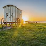 Holzhütte mit Rädern am Strand bei Sonnenuntergang.