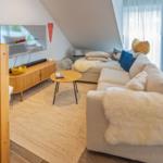Wohnzimmer mit Sofa, Fernseher und Holztreppe