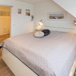 Schlafzimmer mit Doppelbett, Schlafcouch und Bad im Hintergrund.