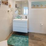 Badezimmer mit Waschbecken, Spiegel, Dusche und Teppich